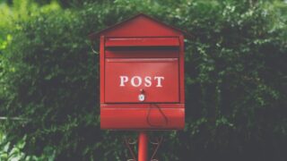 red wooden mailbox near green leaf plant